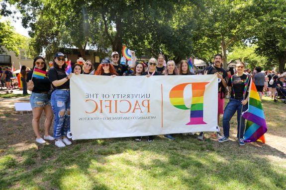A group of people pose with a pride banner