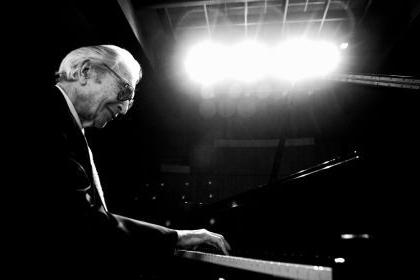 Dave Brubeck is pictured in black and white playing a piano